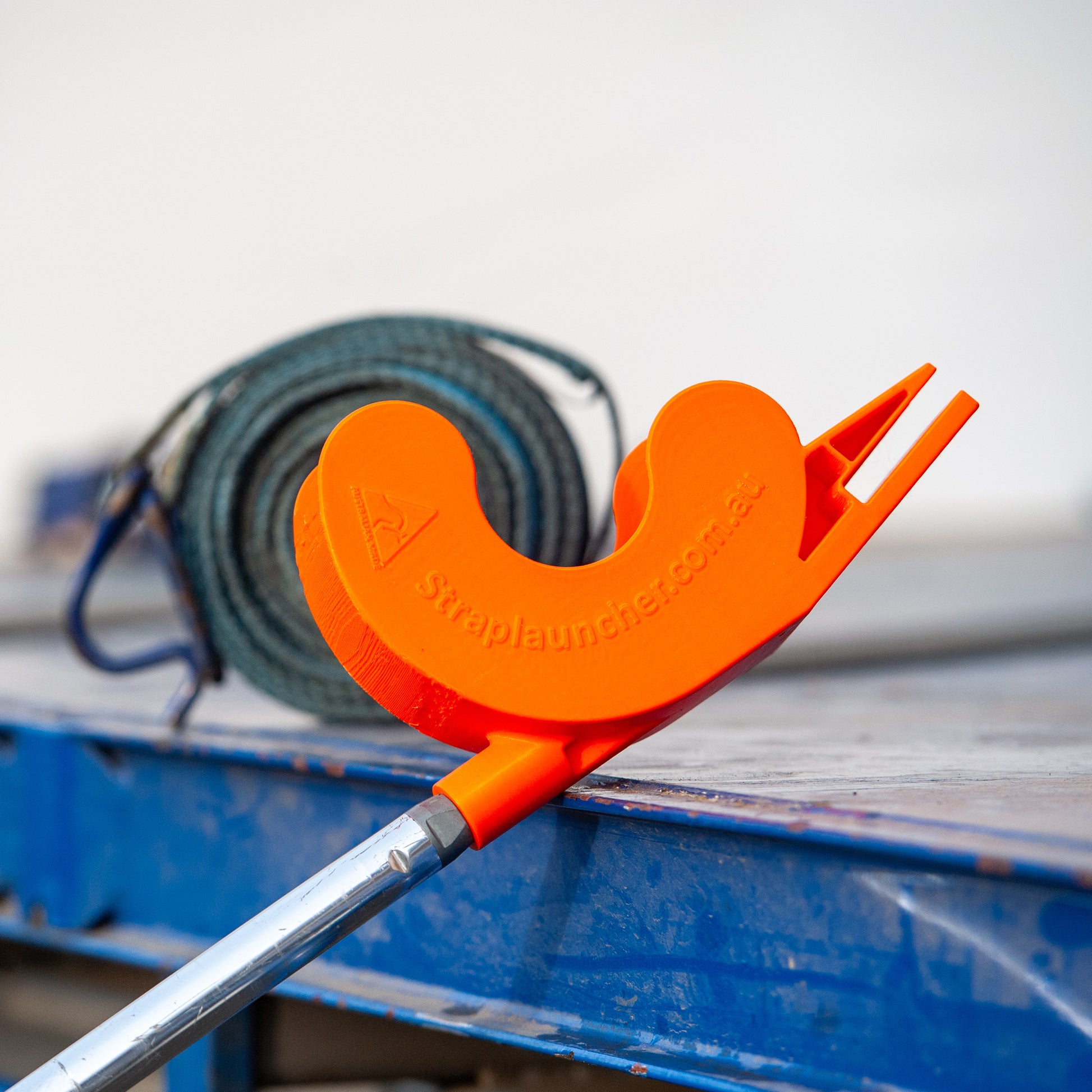 Orange strap launcher tool on a blue surface with a white background
